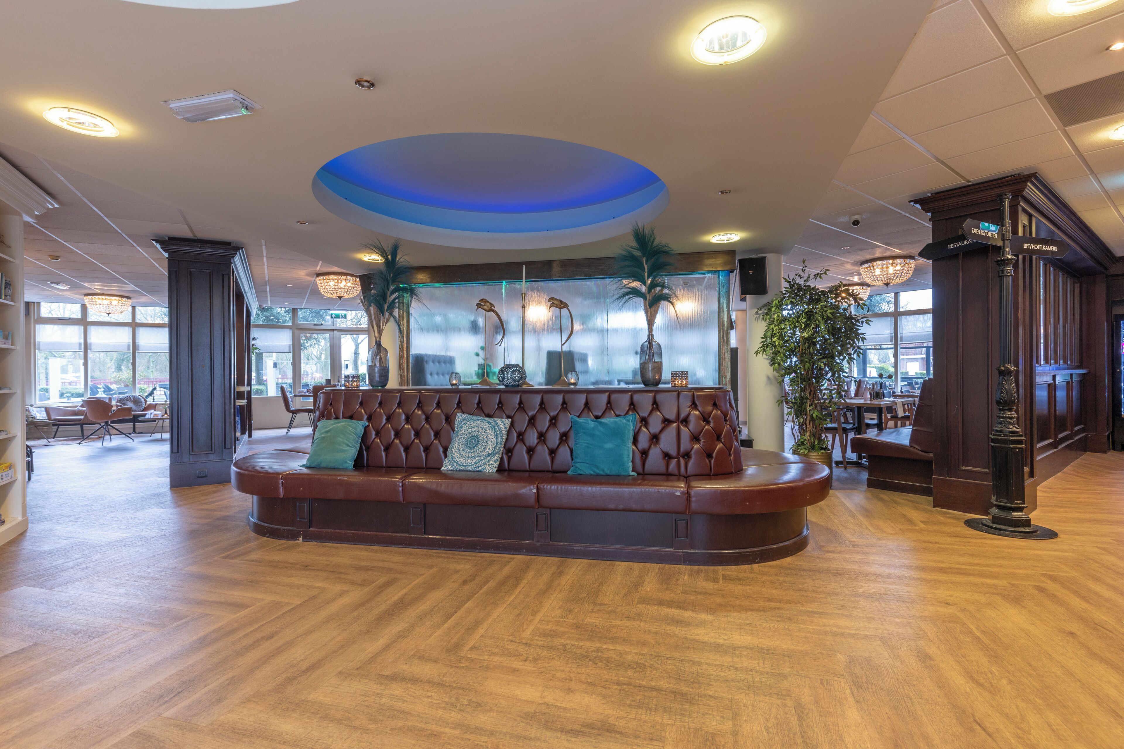 Eine geräumige Lobby mit einer Ledersofa, Holzböden und einem blauen Akzent an der Decke.