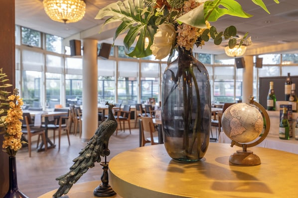 Ein Essbereich mit einer großen Blumenvase, einem Globus und einer Vogelstatue auf einem Tisch.