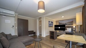 A modern hotel room with a large sofa, a dining table, and a flat-screen TV. - Adventure Awaits: Free Breakfast, Parking & Outdoor Recreation Nearby (Middelburg)