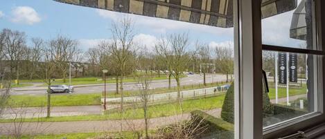 A view from inside a building, looking out at a road with trees and a clear sky.