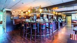 Eine Bar mit hoher Decke, mehreren hängenden Leuchten und einer Bar mit Hockern.