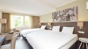 Une chambre d’hôtel avec deux lits, un bureau et une chaise.