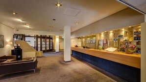 Eine Hotellobby mit Empfangsschalter, einer Treppe und einer Sitzecke.