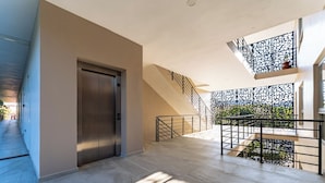 Ein modernes Interieur mit Treppe, Aufzug und einem Balkon mit dekorativer Geländer.