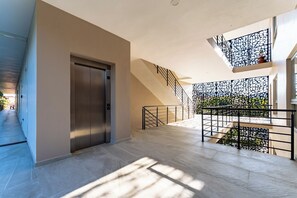 A modern interior with a staircase, elevator, and a balcony with a decorative railing. - 2BR Condo Steps to Beach | Costta A Santa Cruz (Huatulco)