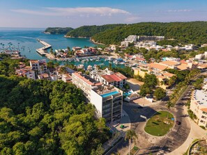Une ville côtière dotée d’un port de plaisance, de bâtiments et d’un grand hôtel avec une piscine sur le toit.