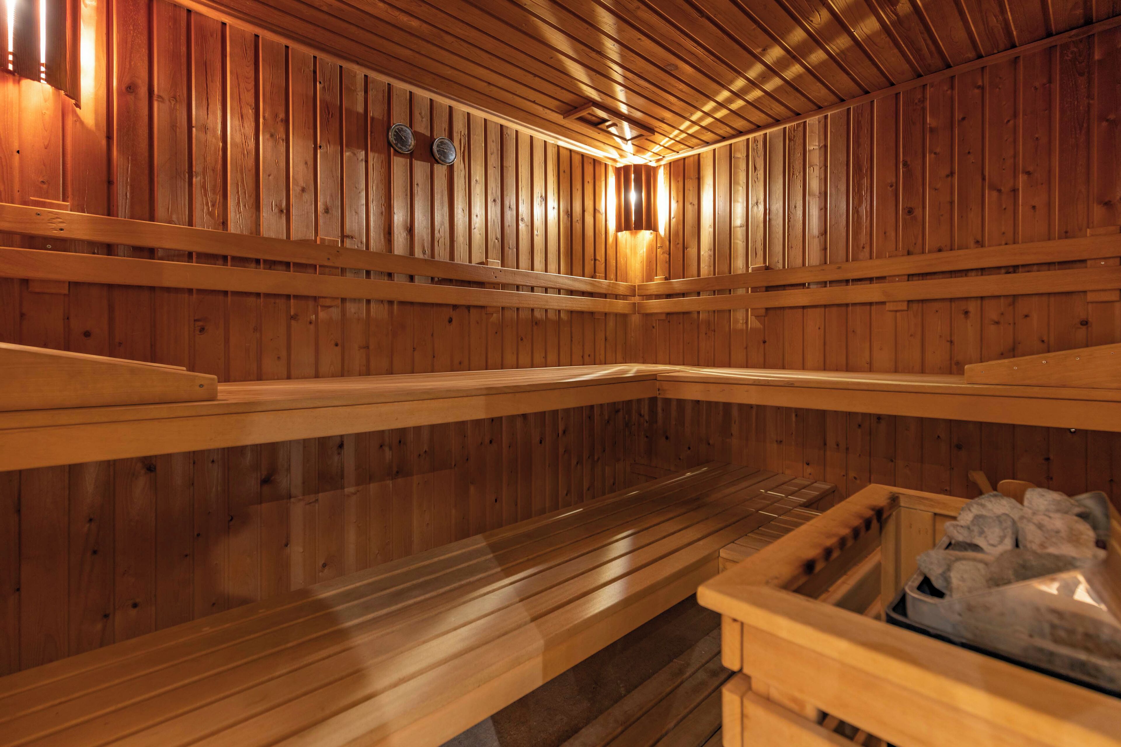 Un sauna avec des bancs en bois et un bassin en pierre.