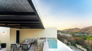 Una terraza en la azotea con piscina, zona de estar y vistas del paisaje circundante.