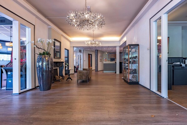 A spacious hallway with a large chandelier, a reception desk, and a glass display case.