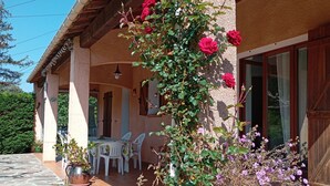A stone-paved patio with a covered dining area, potted plants, and a large vase with flowers. - Provencal House (Bormes les mimosas)