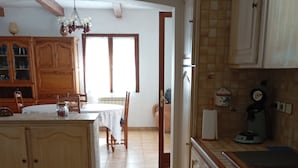 A kitchen with wooden cabinets, a dining table, and a coffee machine. - Provencal House (Bormes les mimosas)