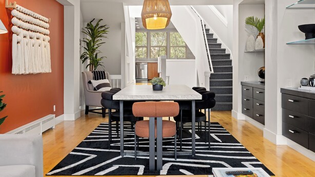 A modern dining area with a white table, black chairs, and a geometric rug. - Global Retreat in the Rockies | Central Location (Denver)