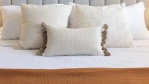 A bed with a grey headboard, white pillows, and a wall-mounted wooden circular decoration. - Global Retreat in the Rockies | Central Location (Denver)