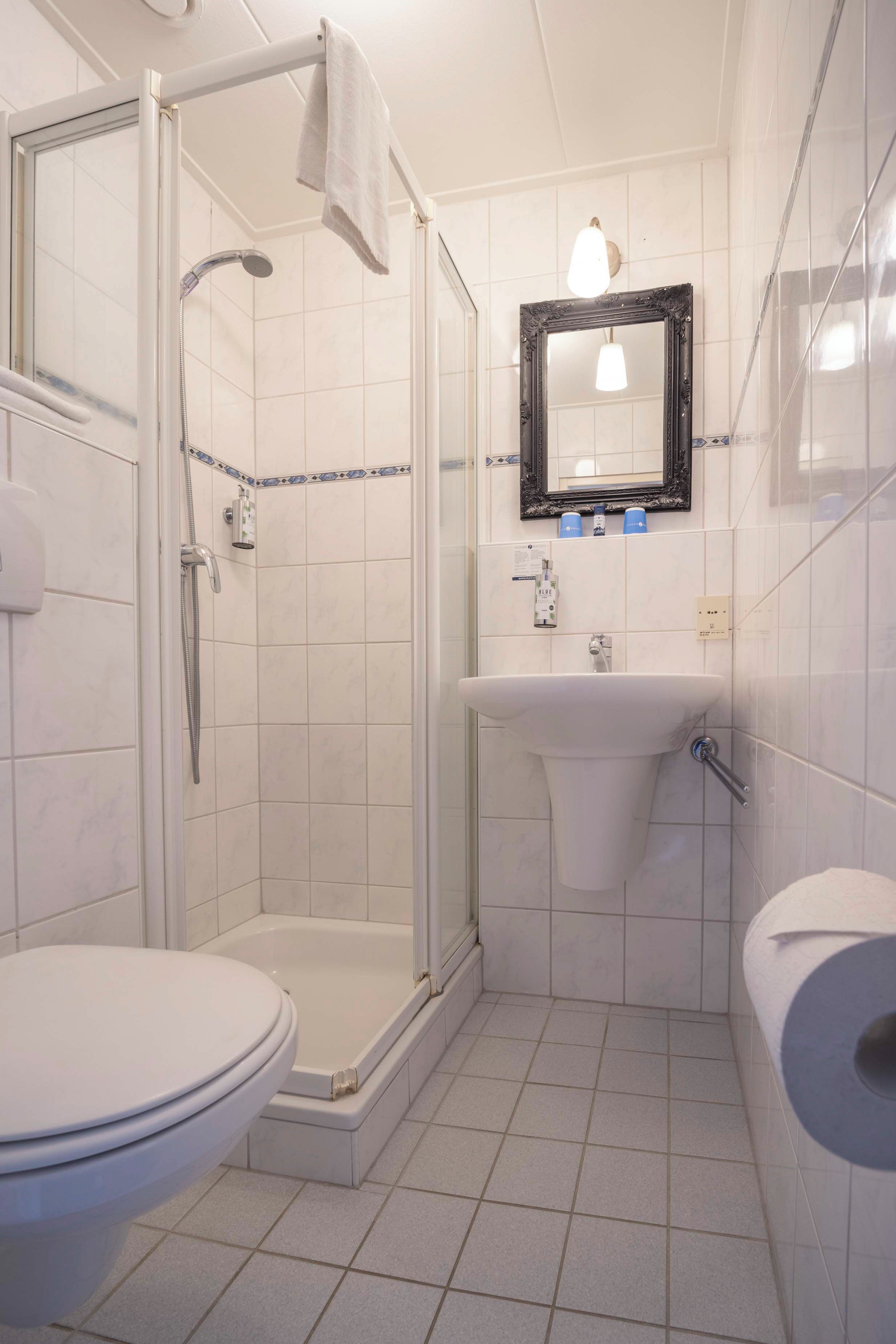 Un baño con ducha envuelta en vidrio, lavamanos e inodoro.
