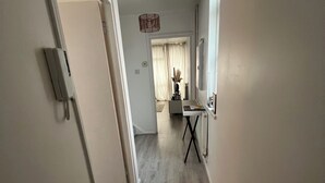 A hallway with a wooden floor leading to a room with a desk and chair. - Lovely 2 bedrom in Vauxhall Central London (London)