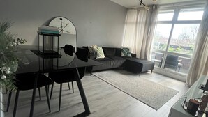 A modern living room with a dining table, black chairs, a black sofa, and a large window with curtains. - Lovely 2 bedrom in Vauxhall Central London (London)