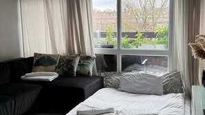 A modern bedroom with a bed, a sofa, a large window, and a ceiling light fixture. - Lovely 2 bedrom in Vauxhall Central London (London)