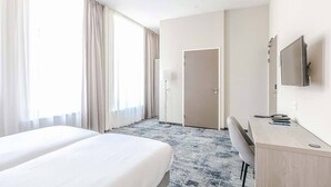 A hotel room with two beds, a desk, a chair, a TV, and a door. - Relax in Historic Luxury with Garden Dining, Near Galleries and Oldehove (Leeuwarden)