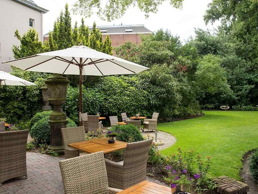 Eine Terrasse im Freien mit Korbmöbeln, einer Stein Säule und einem gepflegten Rasen.