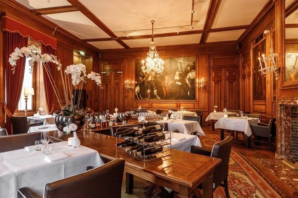 Dine by chandeliers in a richly paneled, intimate setting