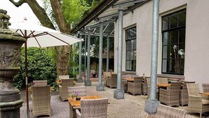 An outdoor patio with wicker furniture, a wooden table, and a stone fountain. - Relax in Historic Luxury with Garden Dining, Near Galleries and Oldehove (Leeuwarden)