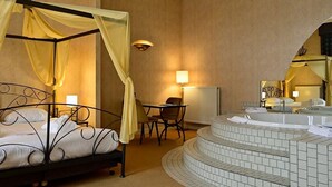Una cama con dosel, una mesita con sillas, una bañera redonda y un espejo.