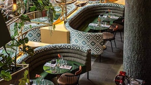 Un restaurante con asientos curvos, lámparas colgantes de vidrio y plantas de interior.