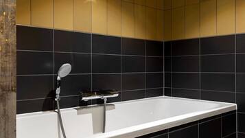Een moderne badkamer met een witte badkuip, zwart-gouden tegels en een handdouche.