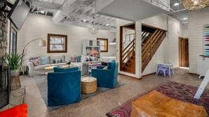 A spacious living area with a sofa, blue armchairs, a coffee table, a patterned rug, and a staircase. - Best Lakeside Living at Big Bend Retreat! (Houston)