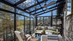 A sunroom with large windows, a ceiling fan, a sofa set, and a small table. - Best Lakeside Living at Big Bend Retreat! (Houston)