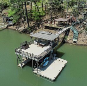 A multi-level dock with a covered seating area and a staircase connecting to a platform.