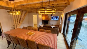 Ein Essbereich mit Holztisch und Stühlen, Kamin und Fernseher.