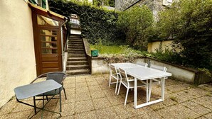 Un patio con una mesa y sillas, una puerta y una escalera que sube a un nivel superior.