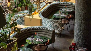 Een restaurant met gebogen zitplaatsen, hangende glazen bollen en kamerplanten.