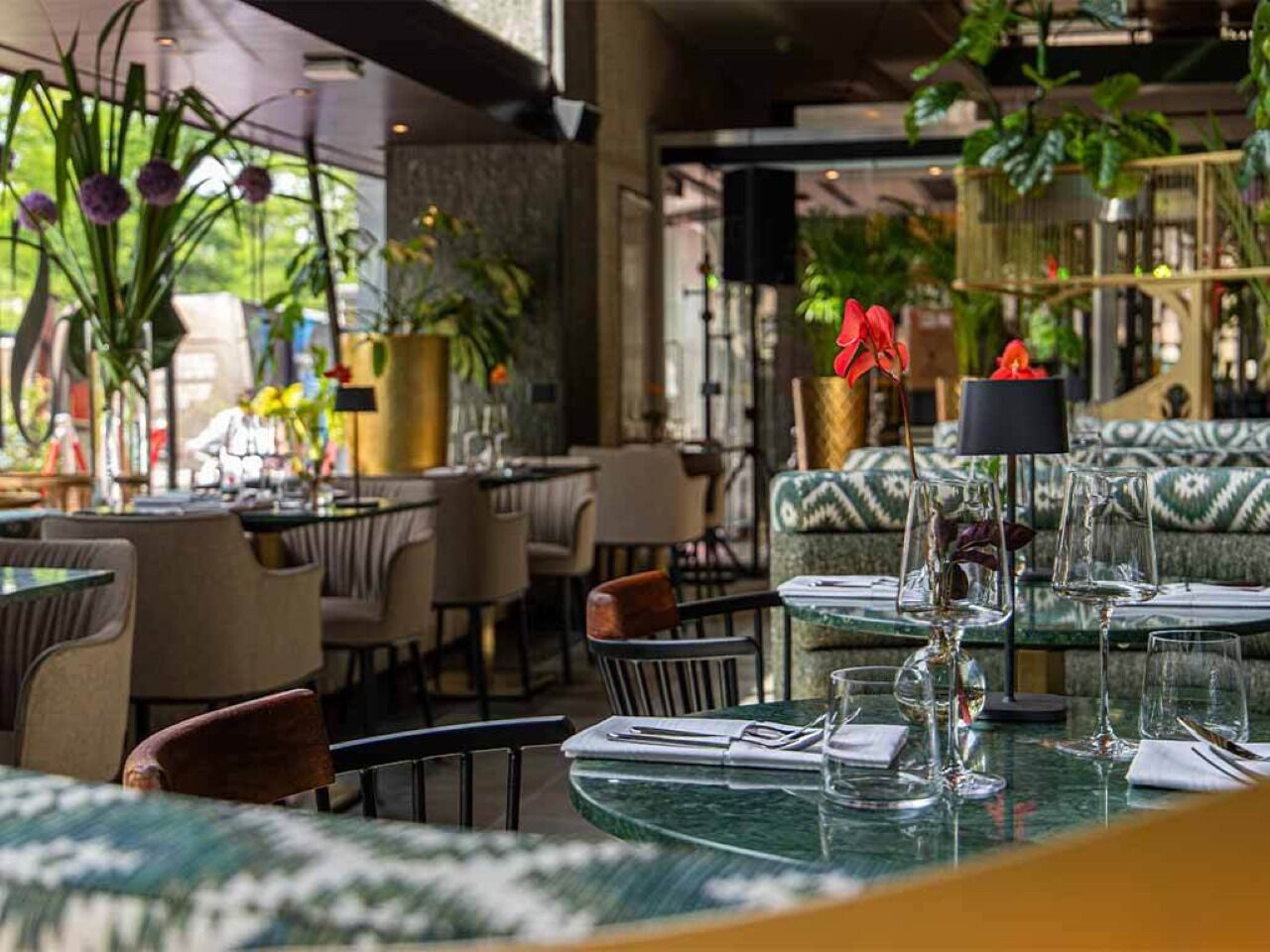 Un restaurant amb taules rodones, cadires i plantes en testos.