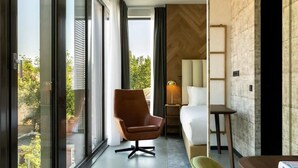 A modern hotel room with a large sliding glass door, a brown leather chair, a white sofa, and a small table. - Indulge in Spacious Rooms – Steps from Historic Attractions - 4 Units (Rotterdam)