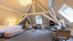 Ein moderner, geräumiger Raum mit Galeriedecke, einem großen Bett, einer Sitzecke und einem Fernseher.
