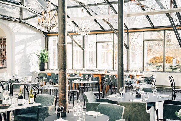 Un restaurante con techos altos, ventanas amplias y mobiliario moderno.