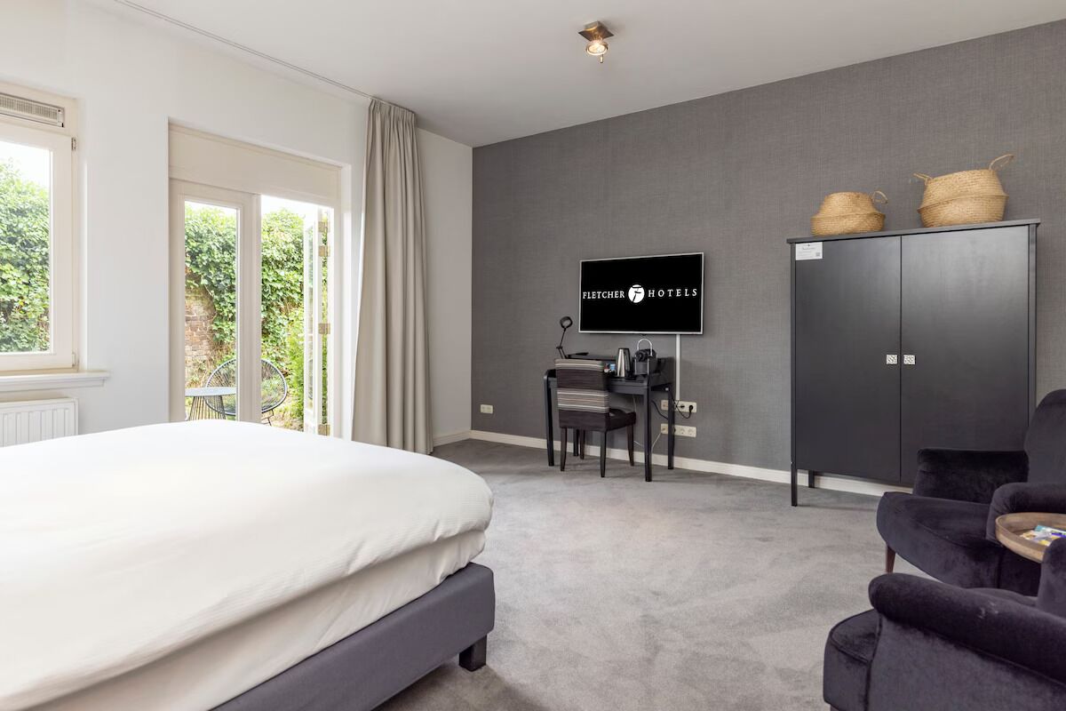 Une chambre d’hôtel avec un lit, un bureau, une télévision et une armoire.