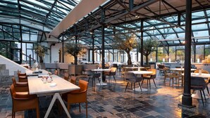 An indoor dining area with tables and chairs, a glass ceiling, and a stone floor. - Comfortable Stay! Free Parking, Onsite Dining! Close to Stuw Belfeld! (Baarlo)
