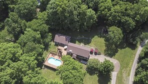 An aerial view of a house surrounded by dense trees, with a swimming pool and a large deck area. - Franklin 6-Acre Mini Farm w/ Pool, Sheep & Goats, Game Room (Franklin)
