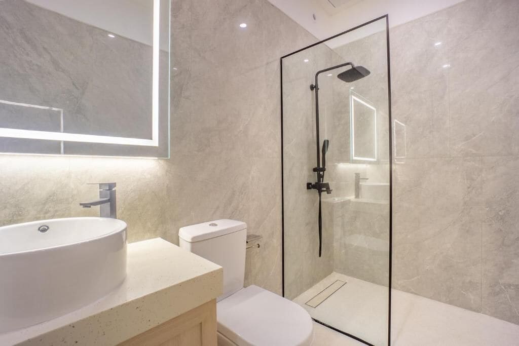 A modern bathroom with a glass-enclosed shower, a round sink, and a toilet.