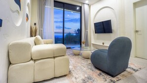 A modern living room with a sofa, armchair, and a glass coffee table. - White Residence (KUTA SELATAN)