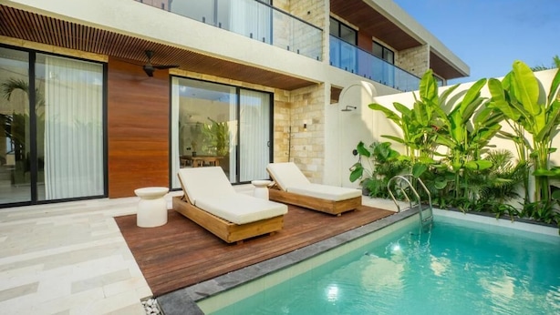 A modern building with a swimming pool, lounge chairs, and a wooden deck. - White Residence (KUTA SELATAN)