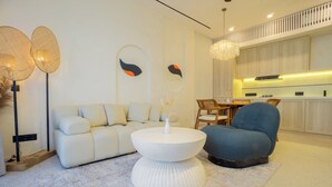 A modern living room with a sofa, a round coffee table, and a blue armchair. - White Residence (KUTA SELATAN)