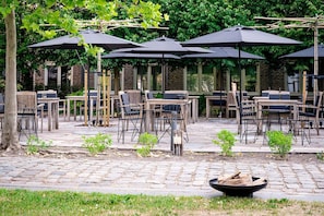 Un patio al aire libre con varias mesas y sillas, rodeado de sombrillas.
