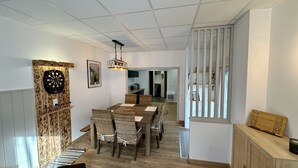 A dining area with a wooden table and chairs, a dartboard, and a hanging light fixture. - Retreat With Terrace, Parking (Mont-Dore)