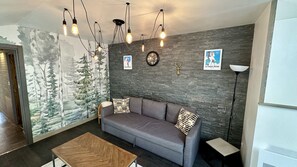Ein modernes Wohnzimmer mit grauem Sofa, einem Holztisch und einer Baum-Mural.