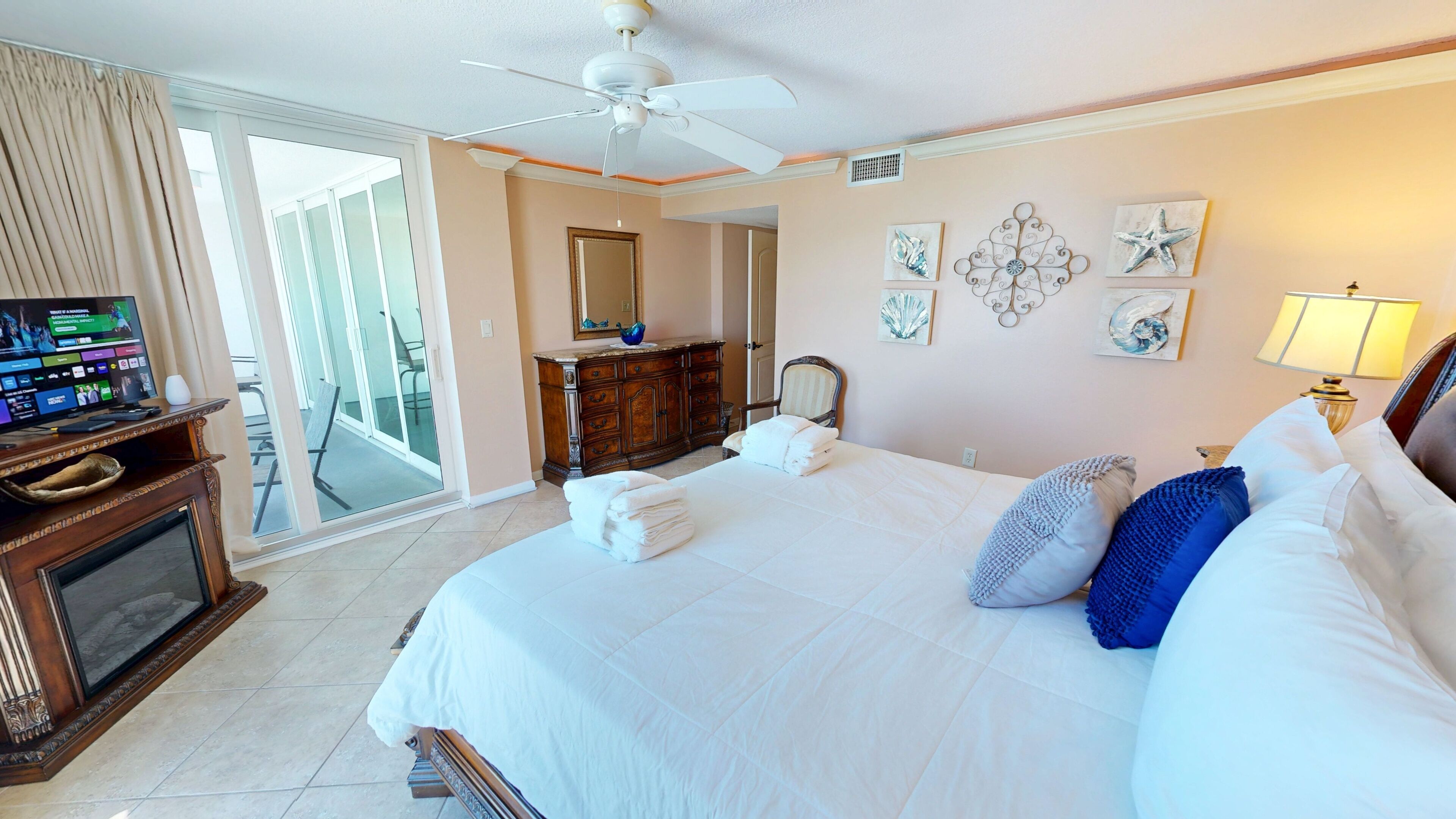 A hotel room with a bed, a television, a dresser, a chair, and a balcony.