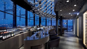 A modern bar with a panoramic city view, a unique ceiling design, and a variety of wine bottles. - 2 Modern Haven, Steps from City Center, Shops | Scenic Nature Trails Nearby (Amsterdam)